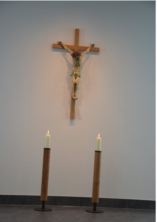Die Kerzenleuchter haben Züge von Baumstämmen. Der alte Corpus ist auf dem neuen Kreuz befestigt und bildet zusammen mit Leuchtern und Ambo eine Einheit.
